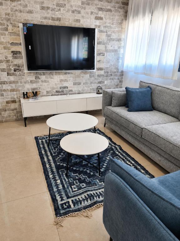 a living room with two couches and a tv at הפינה של פנינה במושבה - דירה משפחתית מהממת in Migdal