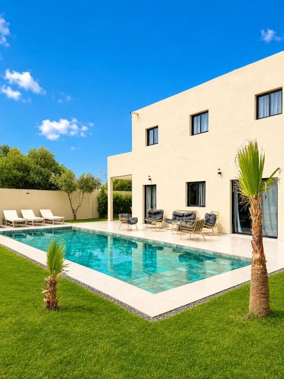 a villa with a swimming pool in front of a building at Villa Elysia in Ech Chaïbat
