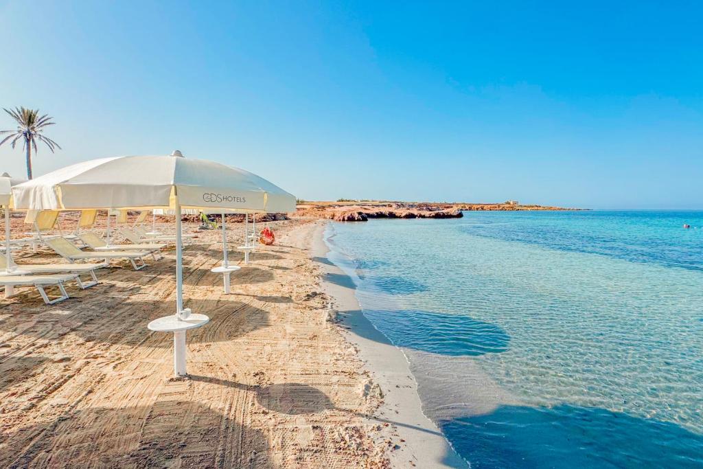 ein Strand mit Stühlen und einem Sonnenschirm und dem Wasser in der Unterkunft Baglio Basile - CDSHotels in Petrosino