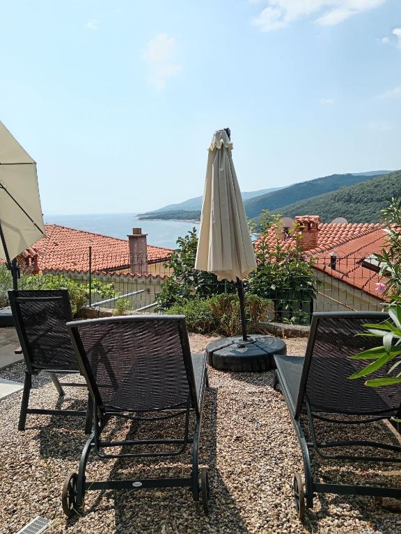 a patio with two chairs and an umbrella at Apartments Zahtila - Pina in Rabac