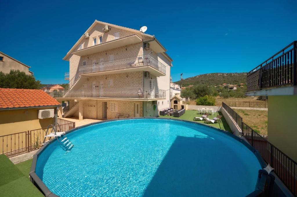 a house with a swimming pool in front of a building at Sun Spalato Mastrinka in Vinišće