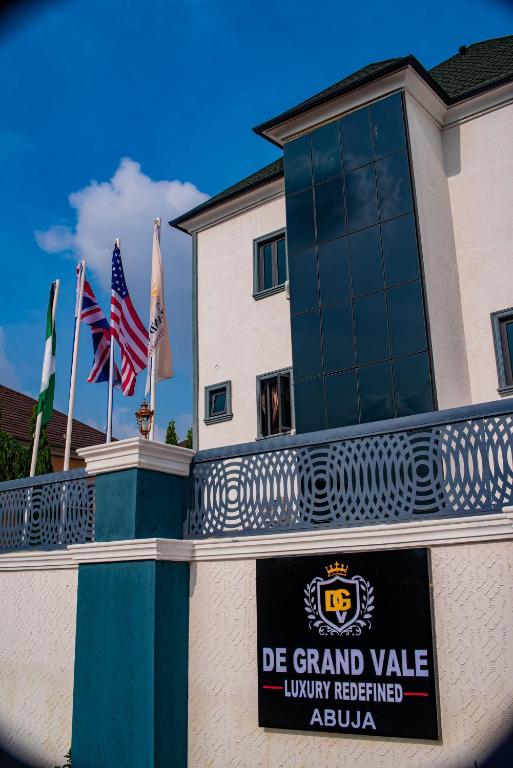 a sign on the side of a building with flags at De Grand Vale Hotel and Suite in Abuja