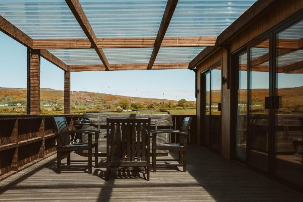 a porch with chairs and a table and windows at Ballyness Guest House in Dungiven