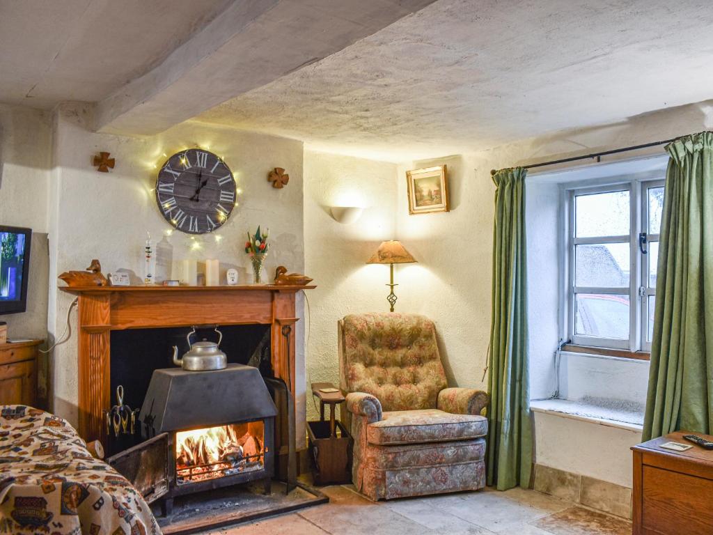 a living room with a fireplace and a chair and a clock at Hoopers Farmhouse - Uk36307 in Tilshead