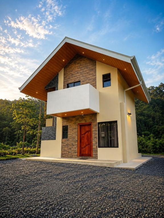 a small house with a red door on a gravel driveway at Casa Colibrí in Bijagua