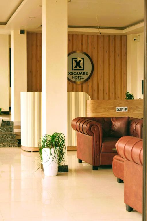 a lobby with a couch and a sign on a wall at Xsquare Hotel in Garubhāsa