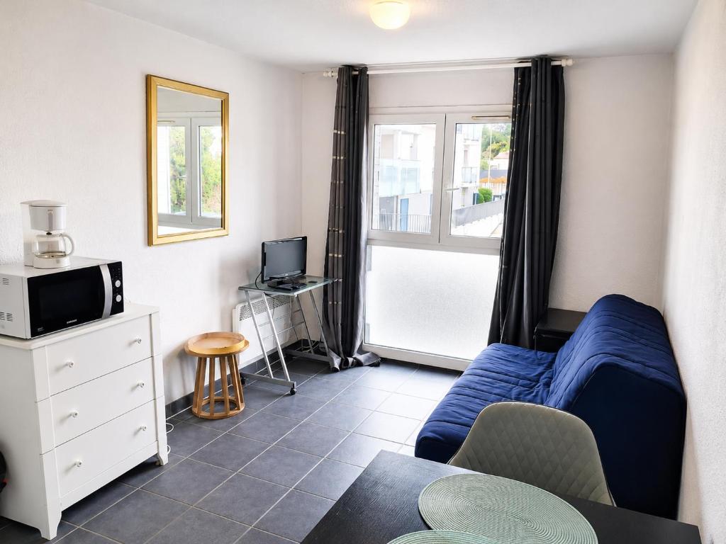 a living room with a blue couch and a tv at STUDIO COSY PROCHE PLAGE, tout à pied in Pornichet