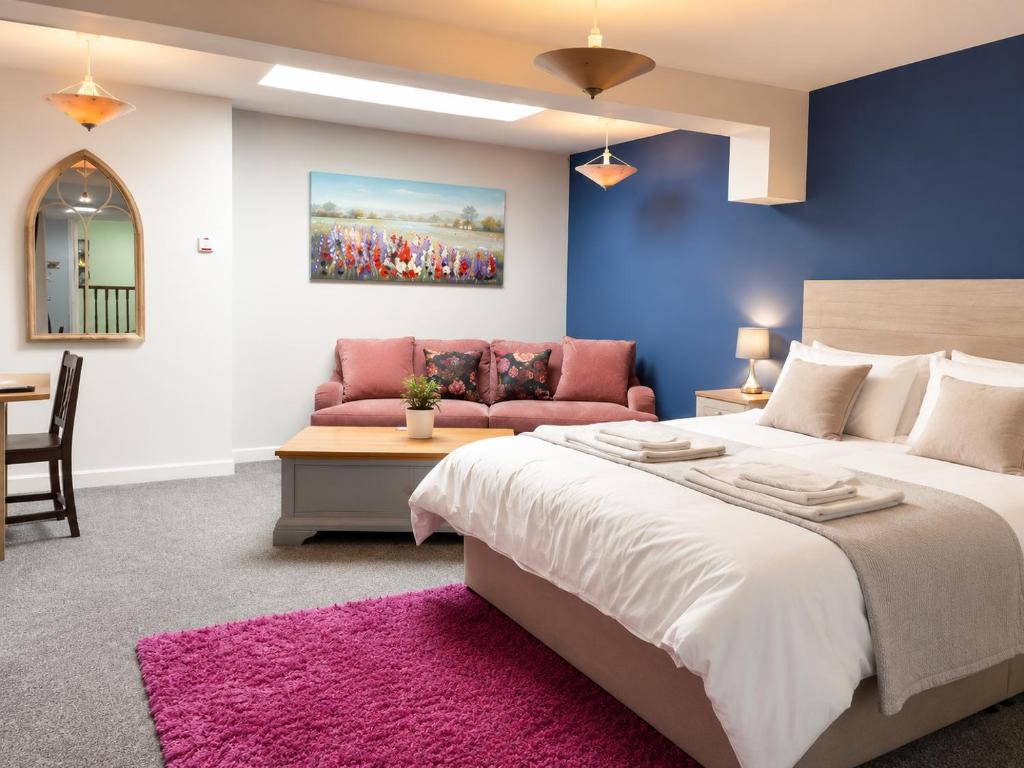 a bedroom with a large bed and a pink couch at Y Teifi in Llandysul