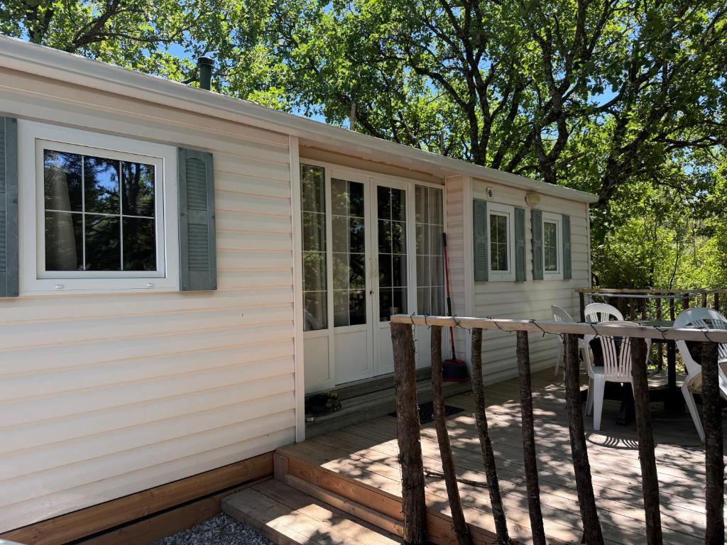 a tiny house with a porch and a deck at Sous les étoiles de St georges in Lazer