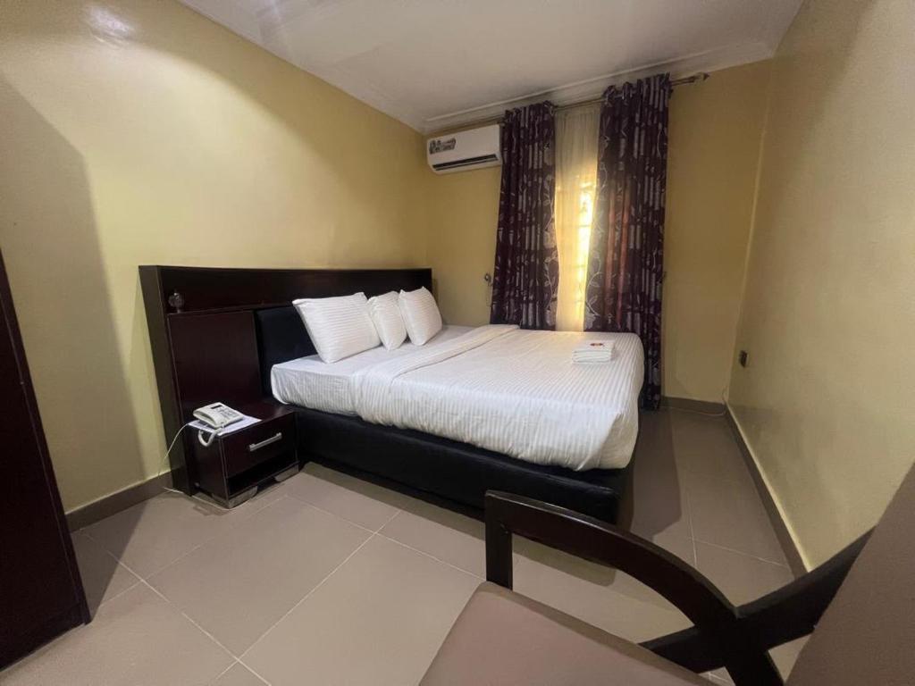a hotel room with a bed and a chair at Excellence Citizens Hotel and Resort in Ilorin