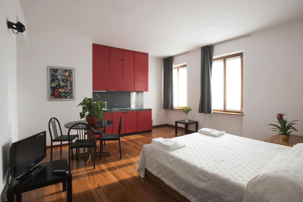 a bedroom with a bed and a kitchen with red cabinets at Residence Villa Odescalchi in Milan