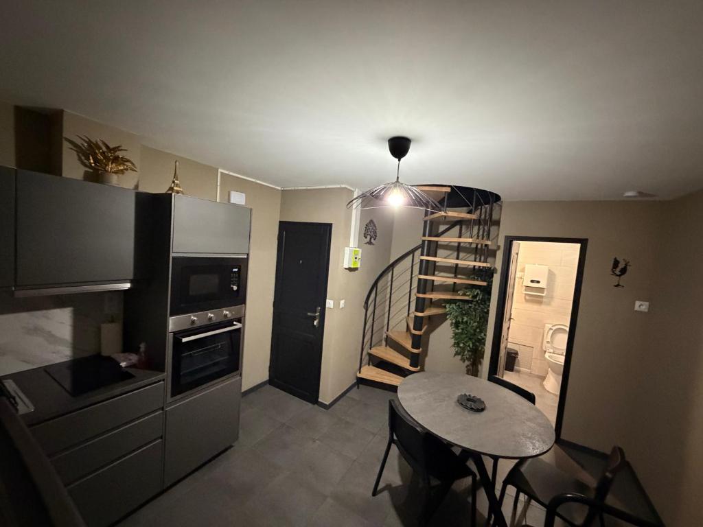 a small kitchen with a spiral staircase and a table at L'Escapade Normande in Caen