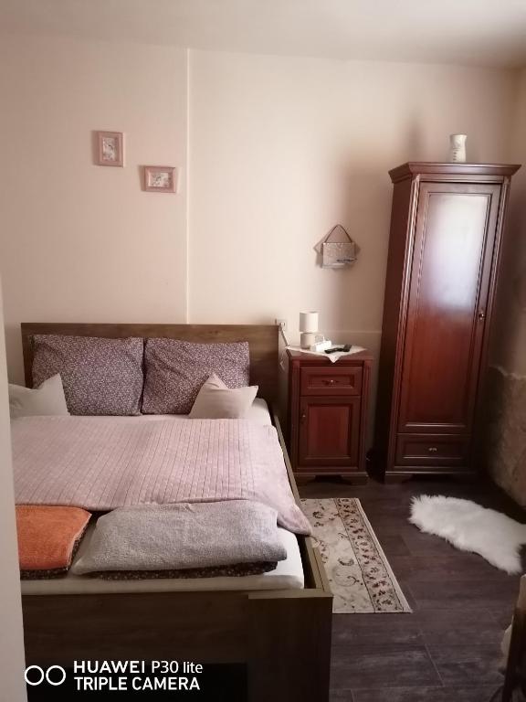 a bedroom with a bed and a wooden cabinet at Nonna Vendégház in Esztergom