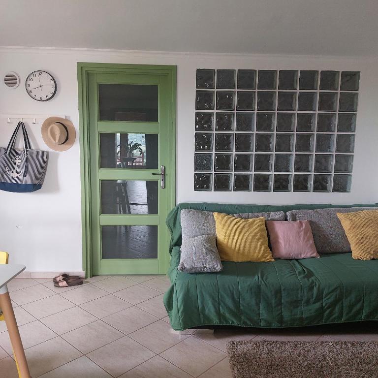 a living room with a green couch and a clock at Panorama Wine & Chill in Hévíz