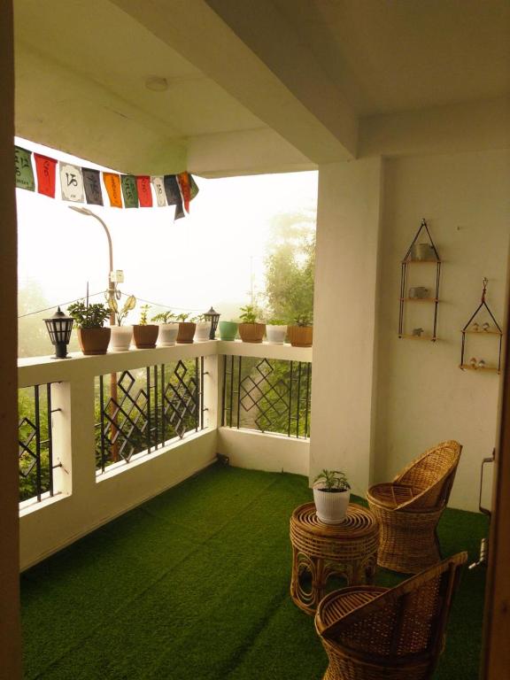 a balcony with a green floor and chairs and a window at Bravo Hills in Gauhāti