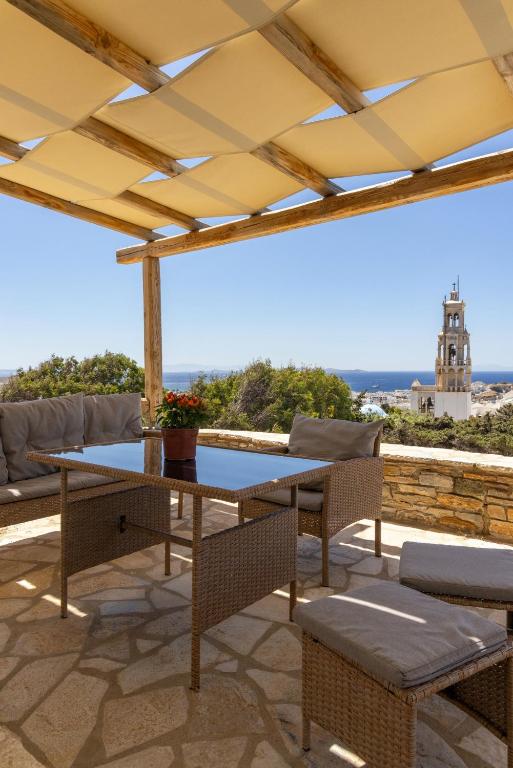 a patio with a table and chairs on a roof at Epavlis Petrou Siwtou in Tinos