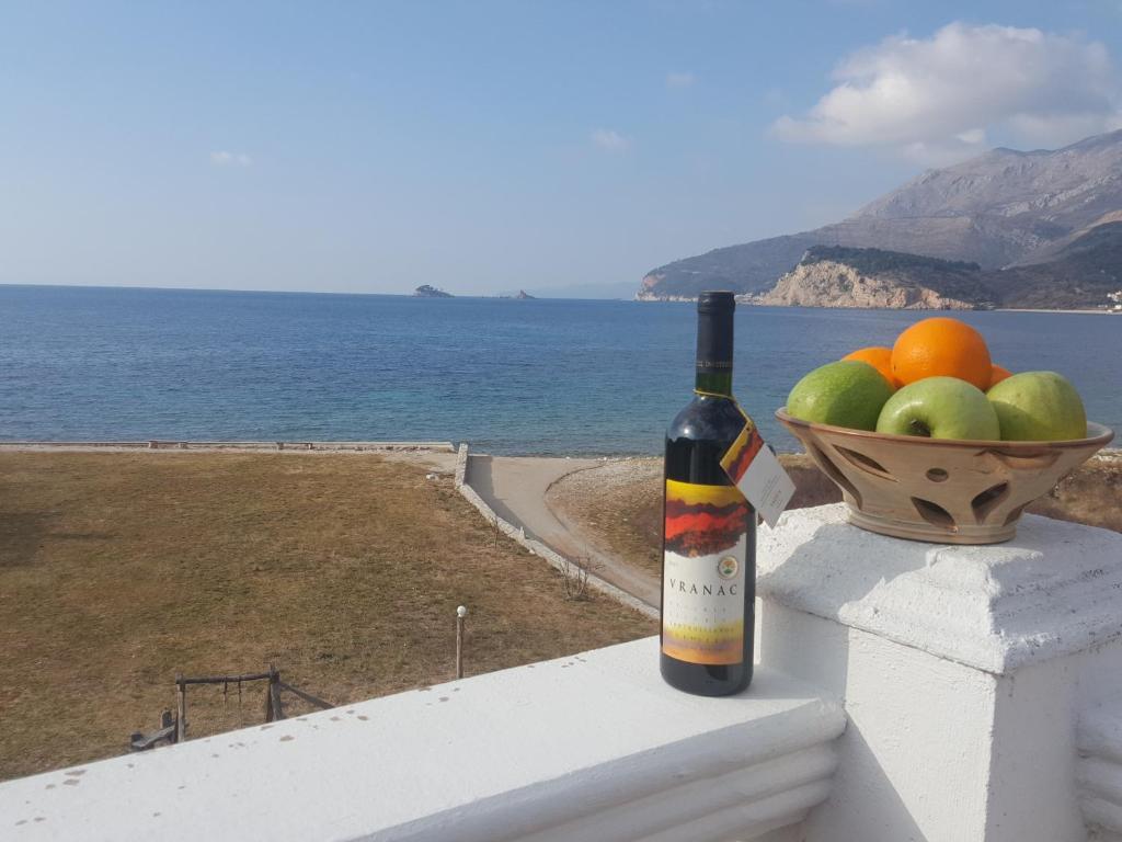 a bottle of wine sitting on a ledge with a bowl of fruit at Buljarica Bay Apartments in Petrovac na Moru