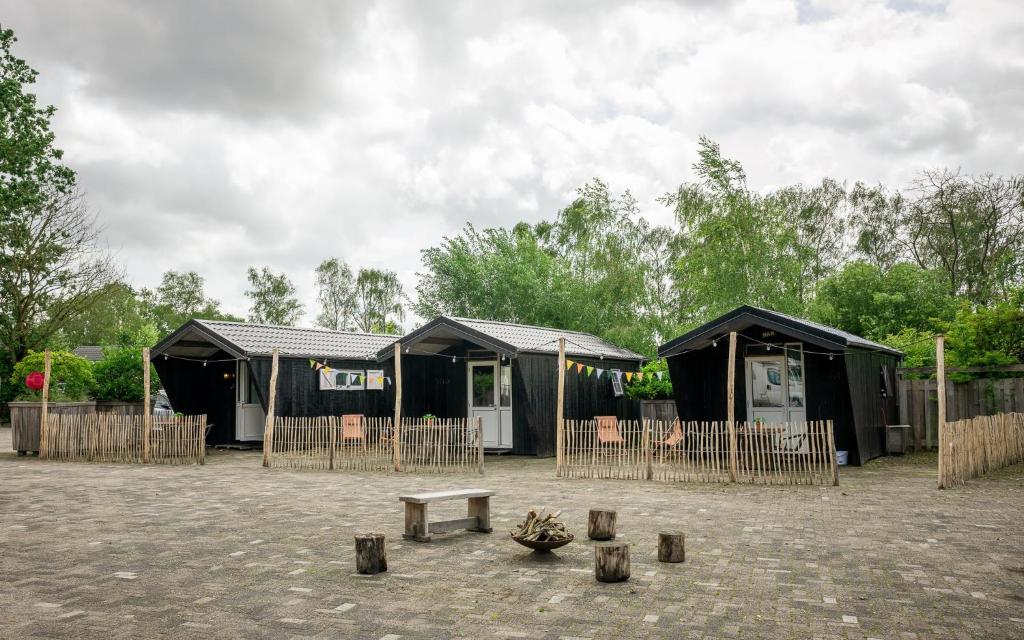 a group of black huts with a bench in a courtyard at Kampeerhut met gedeeld sanitair in Wintelre