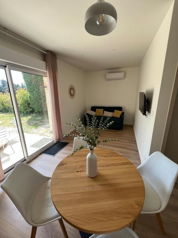 a living room with a wooden table and white chairs at Logement en campagne in Bédarrides