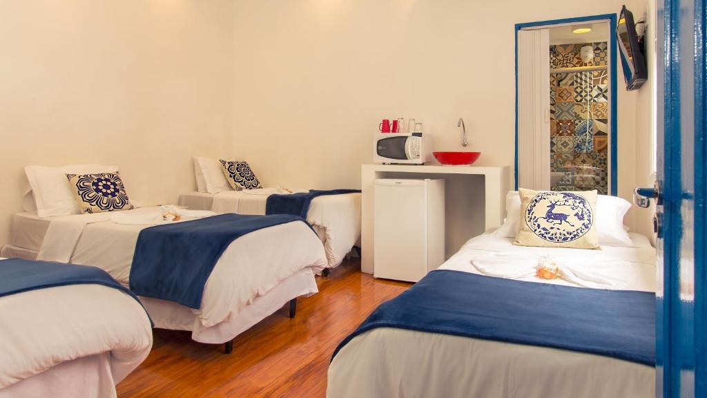 Habitación con 3 camas y almohadas azules y blancas. en Pousada e Hostel São Paulo Comfort, en São Paulo