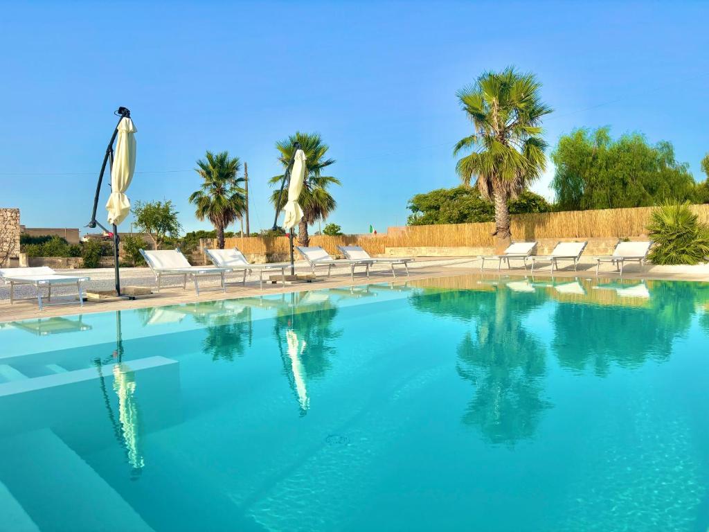 a large swimming pool with chairs and palm trees at B&B Helios in Nardò