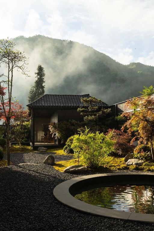 a house with a pond in front of a mountain at Magnolia Maison in Garze
