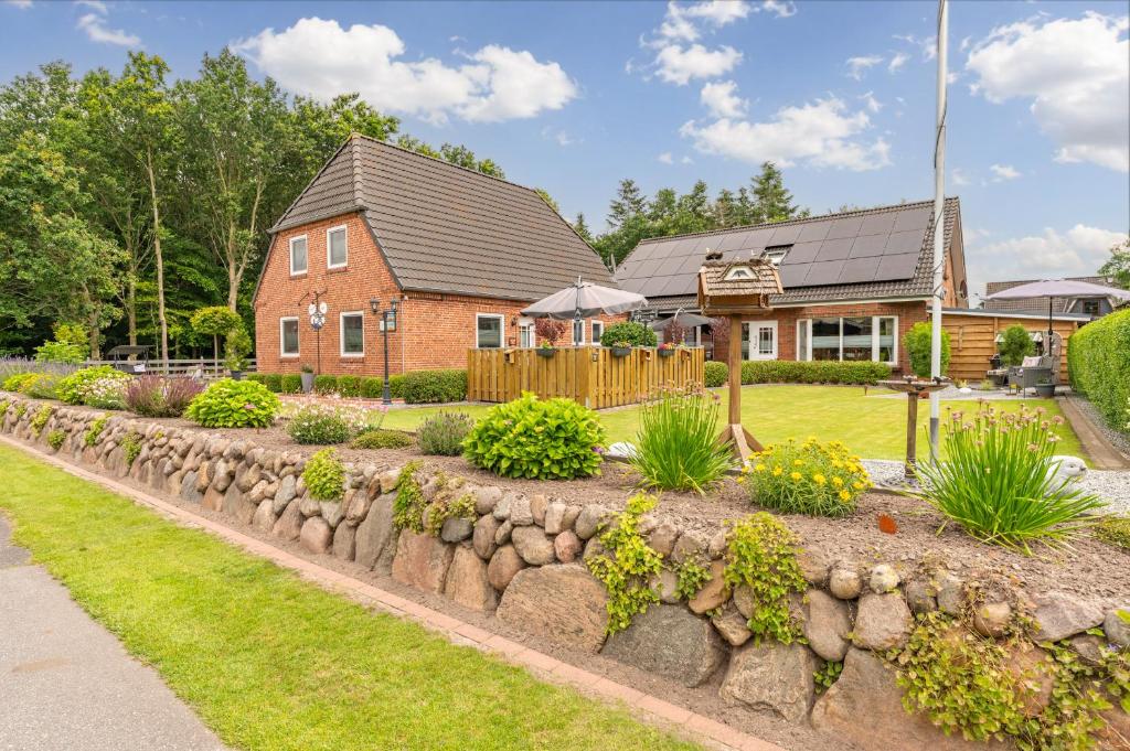a house with a stone retaining wall in front of a yard at Jule Ahoi in Stedesand