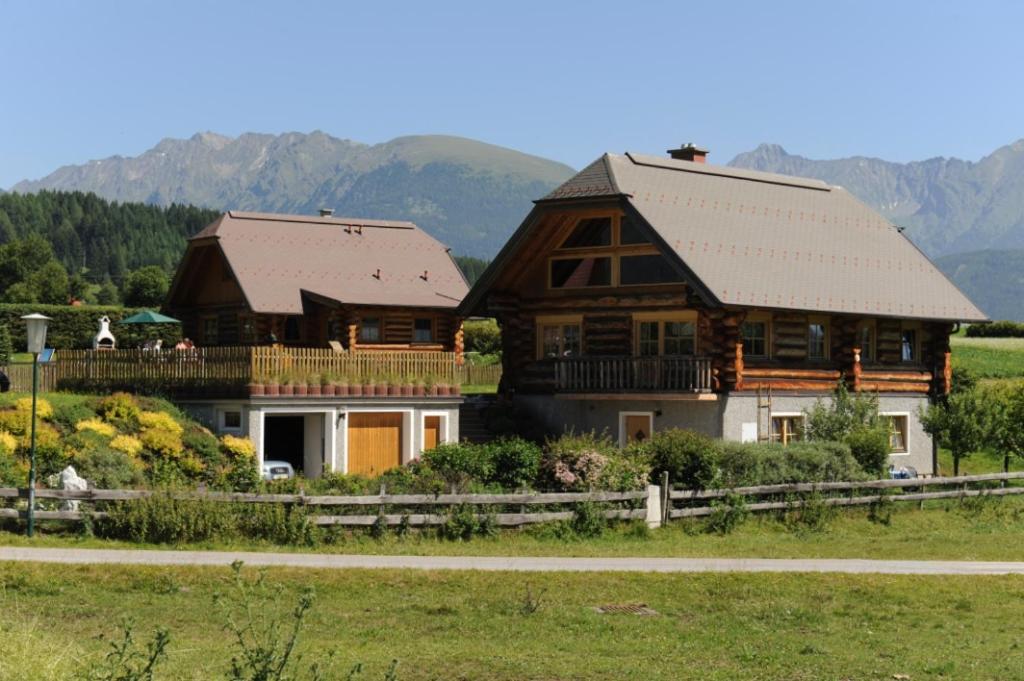 duży drewniany dom na polu z górami w tle w obiekcie Log Home w mieście Mauterndorf