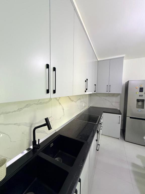 a kitchen with white cabinets and a black sink at Luxurious seaside apartment in Sakës