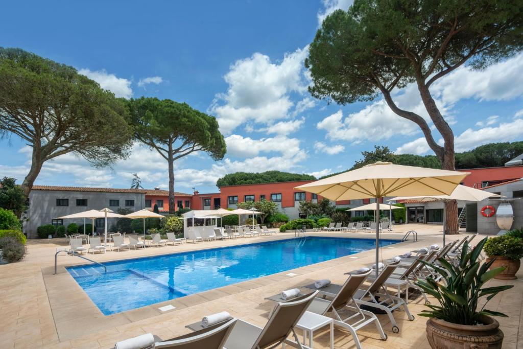 a swimming pool with chairs and umbrellas at Salles Hotel Aeroport de Girona in Riudellots de la Selva