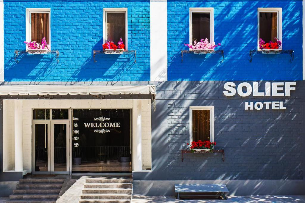 a blue building with flowers in a window at Solief Hotel in Tashkent
