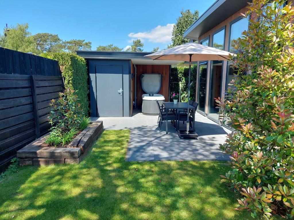 a patio with a table and an umbrella at Comfort bungalow 02 met jacuzzi in Putten