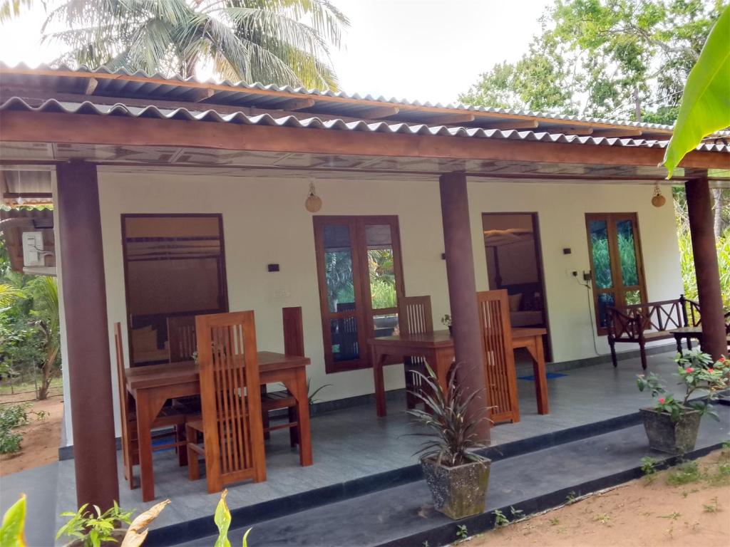 a house with a table and chairs on a porch at Wilpattu Coconut Villa in Nochchiyagama