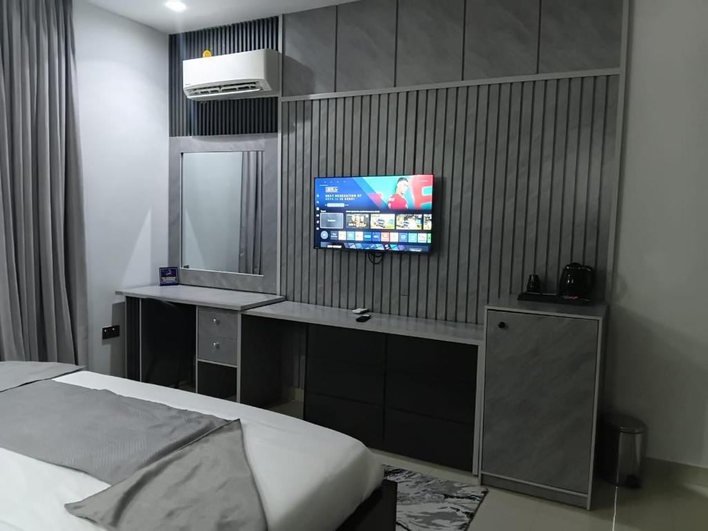 a bedroom with a bed and a tv on the wall at Emirates Star Hotel & Suites in Asaba