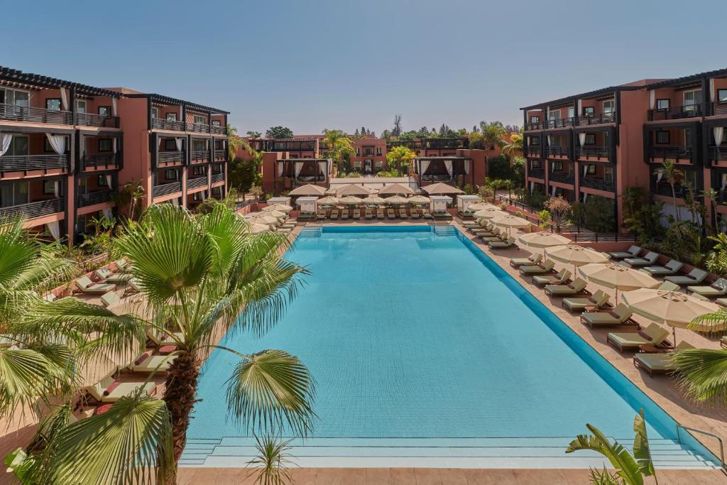 an overhead view of a swimming pool with chairs and palm trees at Hôtel & Ryads Barrière Le Naoura in Marrakesh