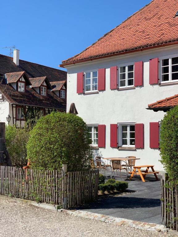 a white building with red shutters and a picnic table at Adler Stetten ob Lontal in Niederstotzingen