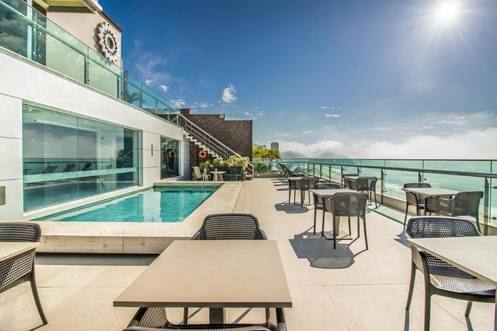 an outdoor patio with tables and chairs and a swimming pool at Arena Copacabana Hotel in Rio de Janeiro