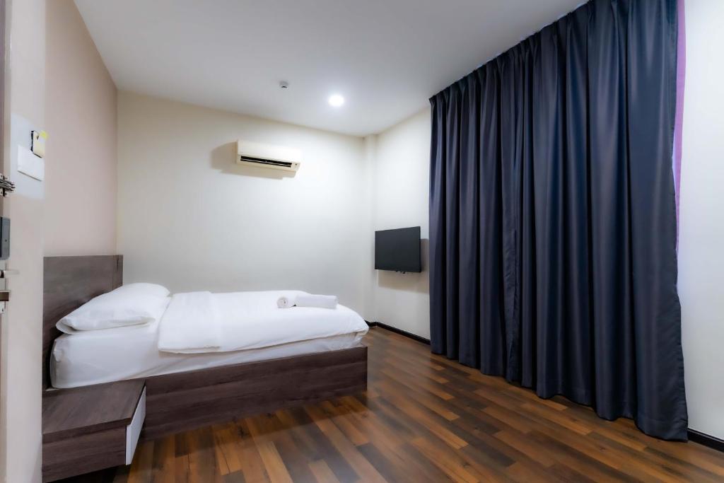 a bedroom with a bed and a black curtain at T Plus Hotel Bagan in Butterworth