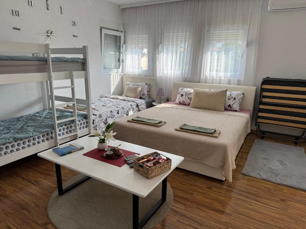 a bedroom with two beds and a table and a bed at Apartment On the way in Stolac