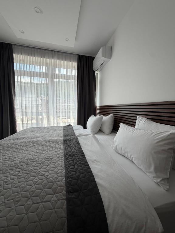 a bedroom with a large bed with white pillows and a window at Sarajevo Center Point in Sarajevo
