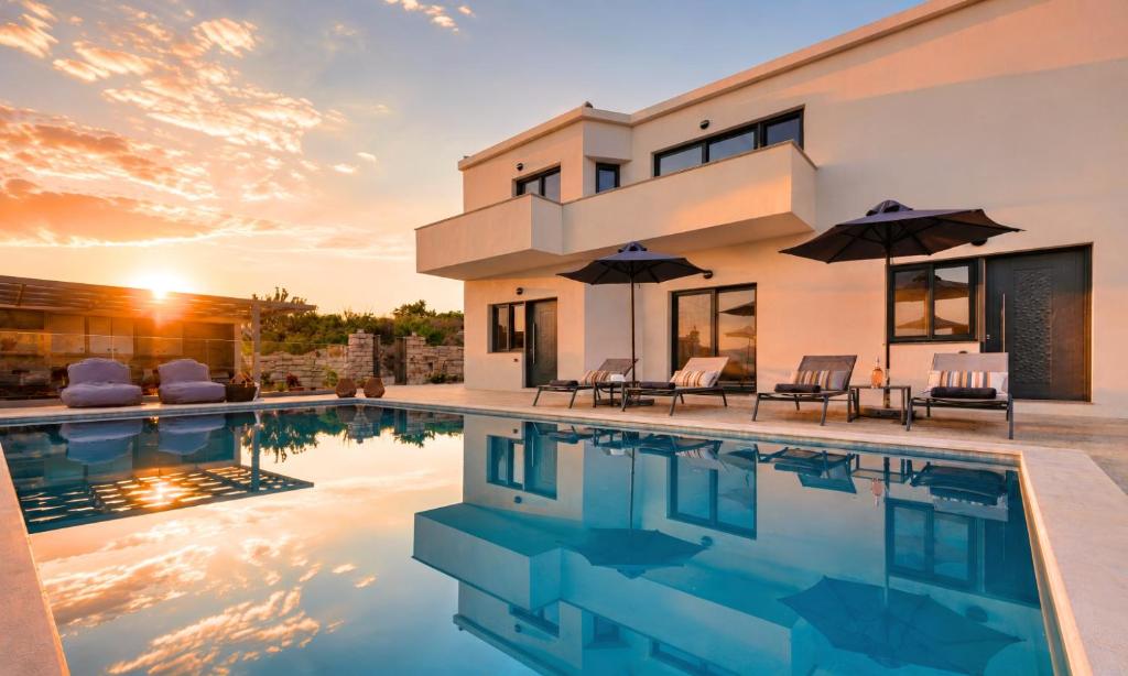 a house with a swimming pool in front of it at Pranvera Villa Sea View & Pool in Dhrámia