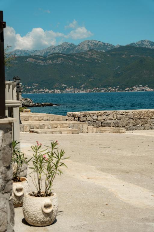 two potted plants sitting on a sidewalk near the water at Sunset Studio Apartments Bjelila in Tivat
