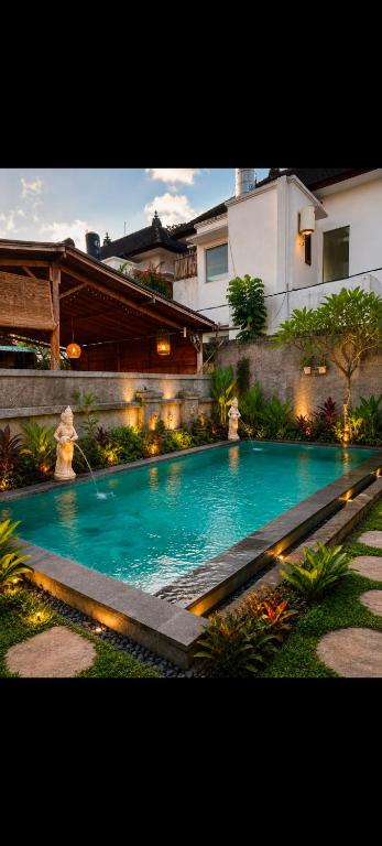 a swimming pool with blue water in front of a building at Uma Kutuh Bungalow in Ubud