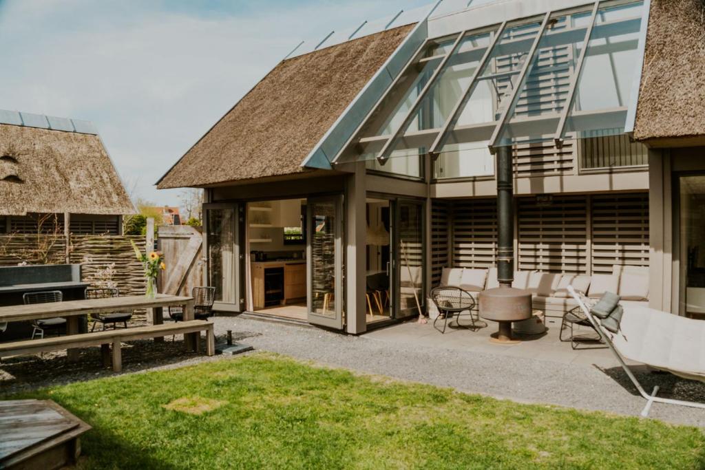 a house with a thatched roof and a patio at Dutchen Vakantiepark Duynvoet in Schoorl