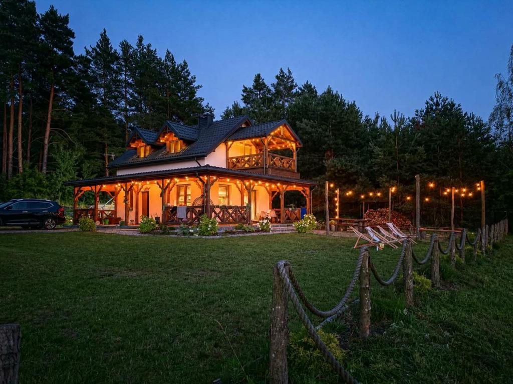 a large wooden house with lights on it at Dom za wydmą in Nielbark