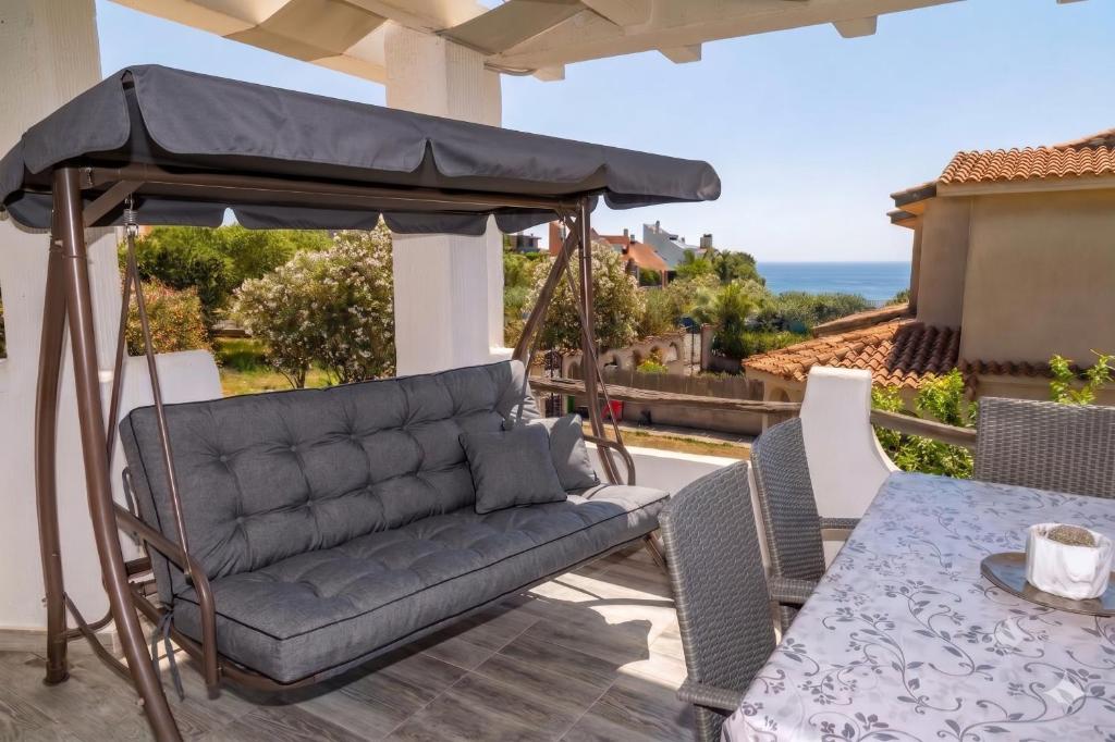 a couch on a patio with a table and an umbrella at Beachfront Luxury Villa Letizia - Sea View Terraces & Green Solar Energy in Quartu SantʼElena