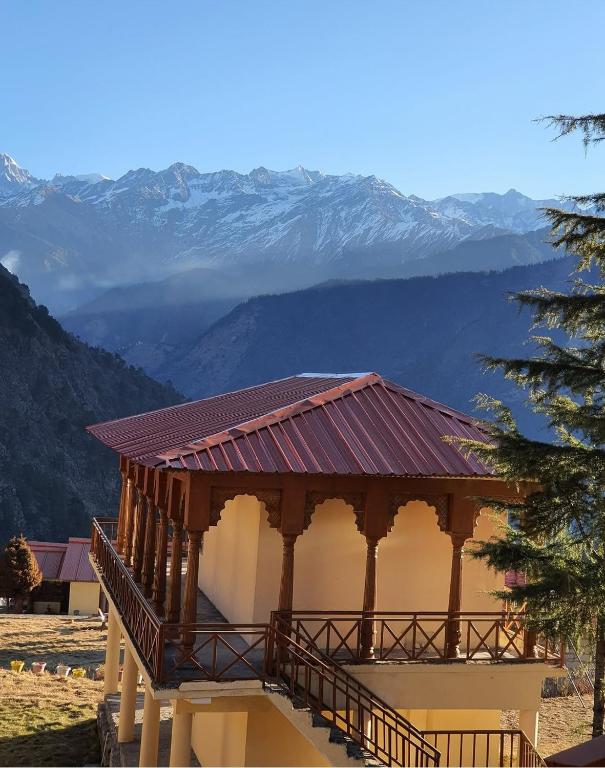 a building with a roof with mountains in the background at Dayara resort in Bhatwāri