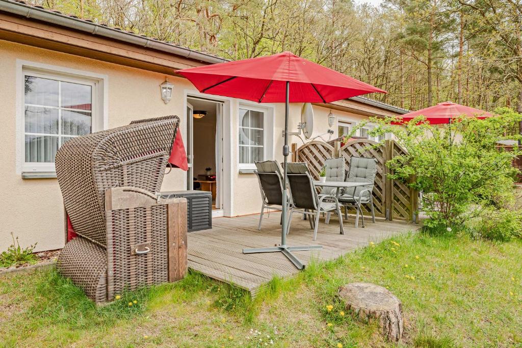 a wooden deck with chairs and an umbrella at Waldsiedlung Waldhaus App 4.2 in Korswandt
