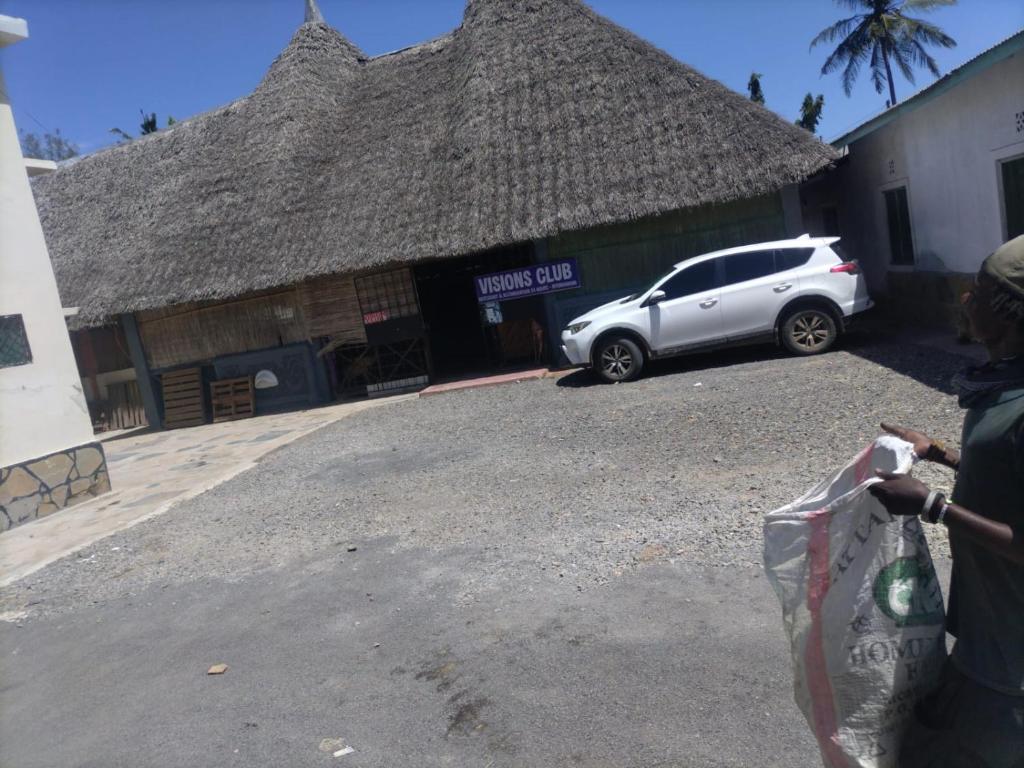 a person standing in front of a building with a car at Mtomo vision in Mtwapa