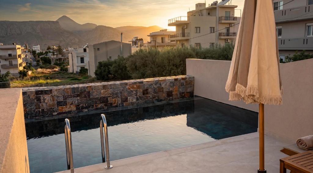 a swimming pool with an umbrella on a building at Eleni Village & Suites in Amoudara Herakliou